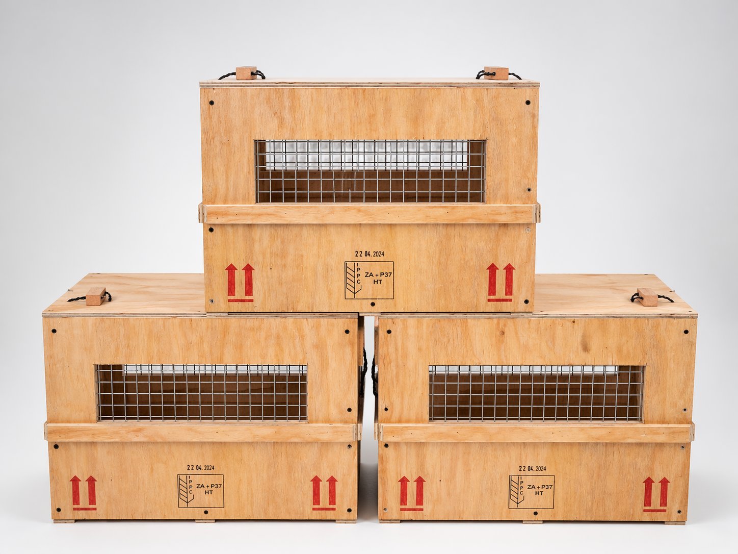 Stacked wooden shipping crates with ventilation grilles and red handling labels arranged in a pyramid formation